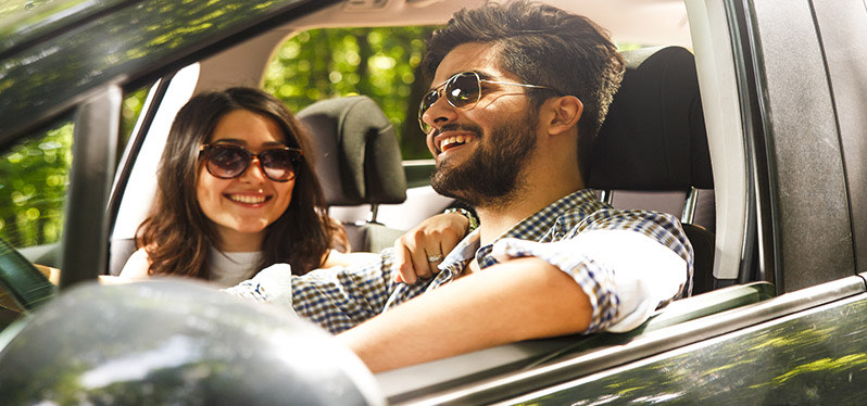 Young couple smiling while driving with the windows down