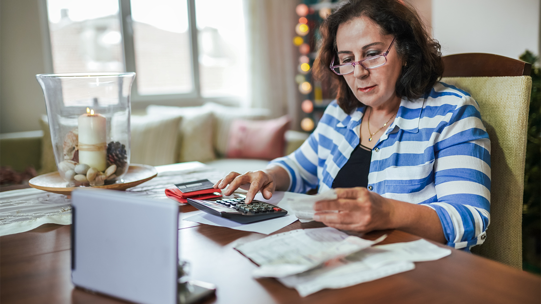 woman using calculator at home to pay bills