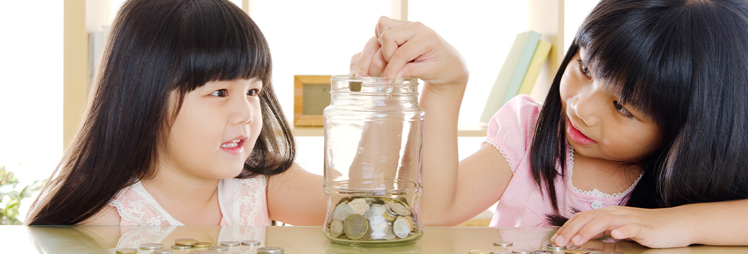 Woman and daughter put money in a jar to save away for later.