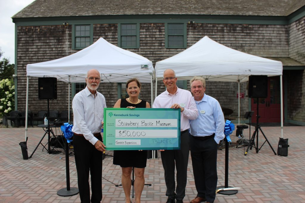 Representatives from Kennebunk Savings and Strawbery Banke pose with a large check for 50,0000 dollars.