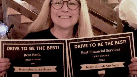 Maureen Flaherty holds up Drive to be the Best Awards for Best Bank and Best Financial Services