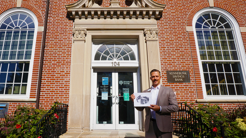 Mark Ross holding a picture of the Main Street location taken in 1929, in front of the location today.