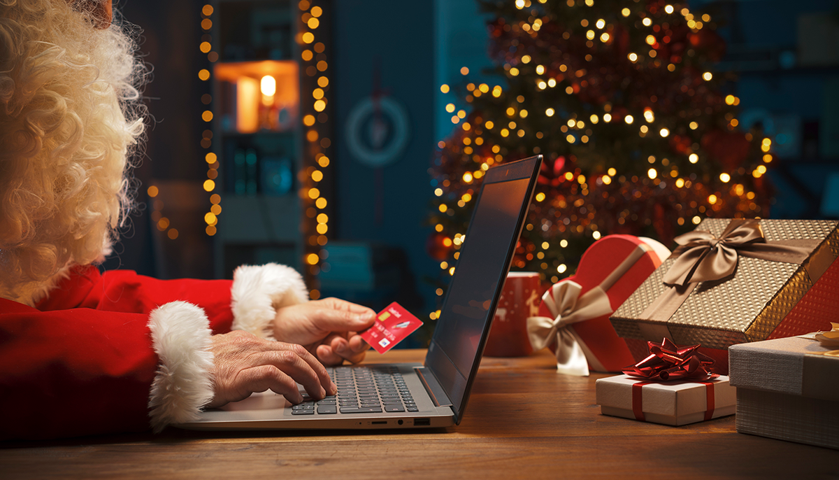 Santa shops online with credit card in his hand