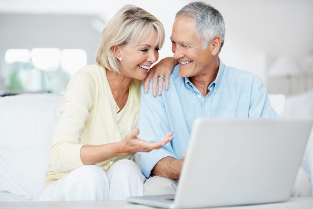 Portrait of a happy senior man with surprised woman while working on a laptop